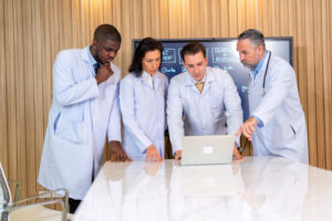 A Group Of Doctors Looks At Laptop Computer Brainstorming Meeting While Listening To Medical Report - Cesanto Assessoria Empresarial | Escritório de Contabilidade na Zona Sul - SP
